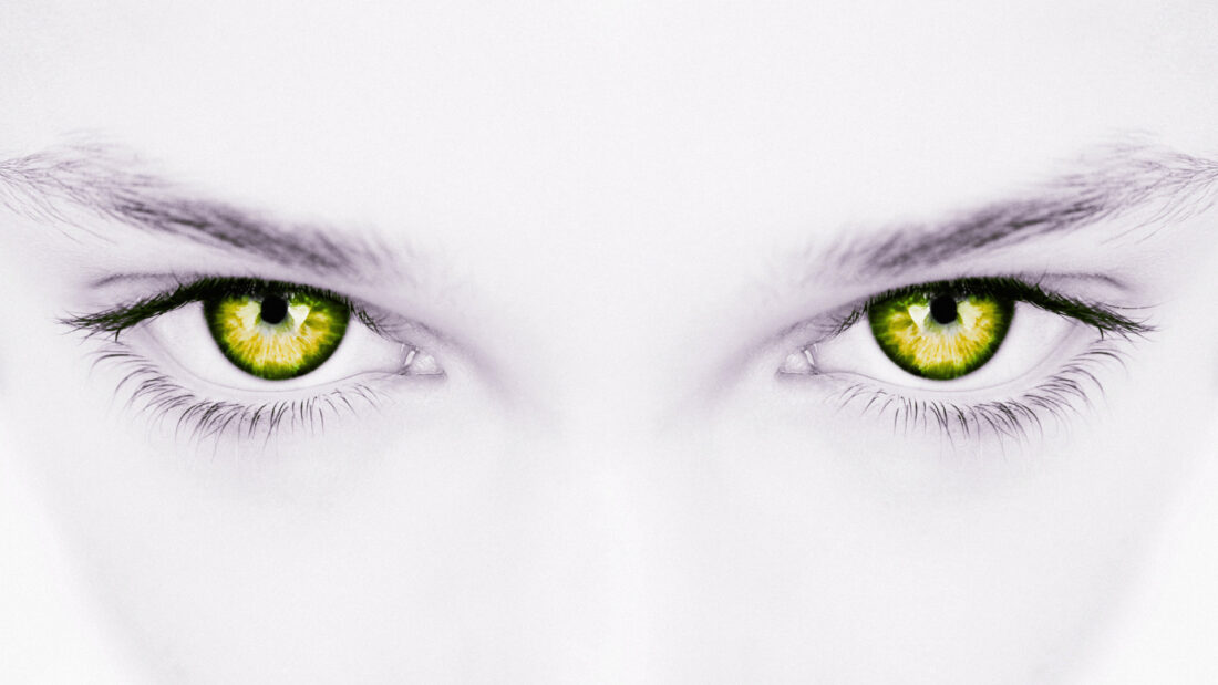 Zbliżenie zielonych oczu w ujęciu symbolicznym, przedstawiające koncentrację i skupienie uwagi - wizualna metafora hipnozy.