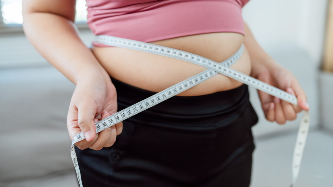 Kobieta mierzy obwód talii centymetrem – hipnoza na odchudzanie i zmiana nawyków żywieniowych