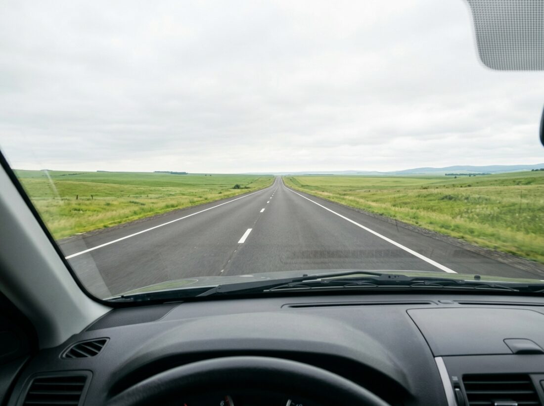Widok z perspektywy jadacego auta na dluga, calkowicie prosta autostrade ciagnaca sie po horyzont,